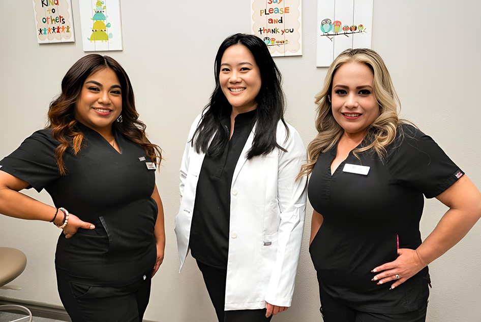 Dentist with two of our dental assistants standing smiling in the operating room